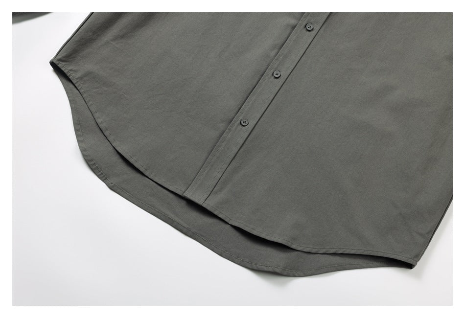 Close-up of the dark gray shirt's curved hem and front button placket.