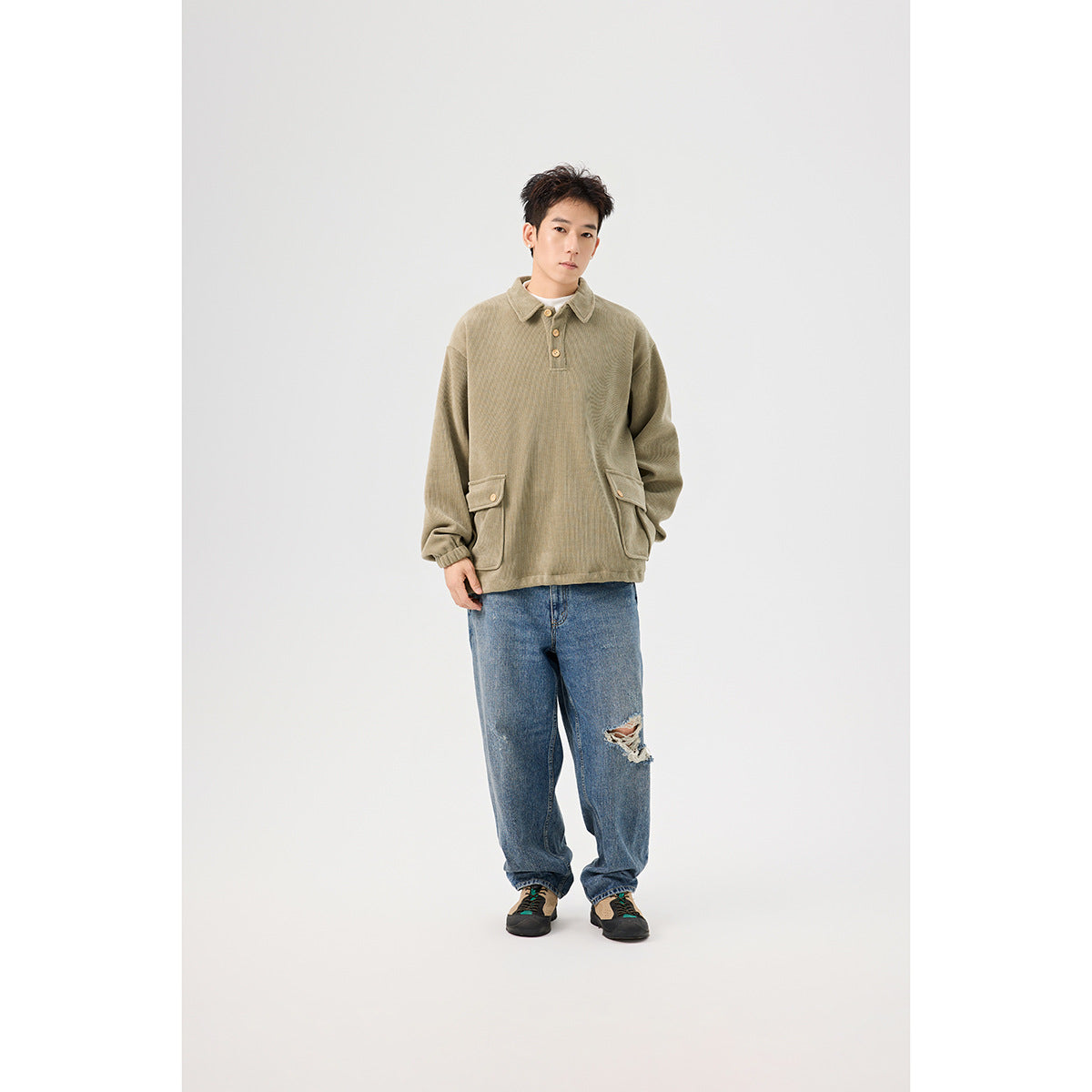 Full-length front view of a model wearing an olive pullover with a collar, button placket and flap pockets.
