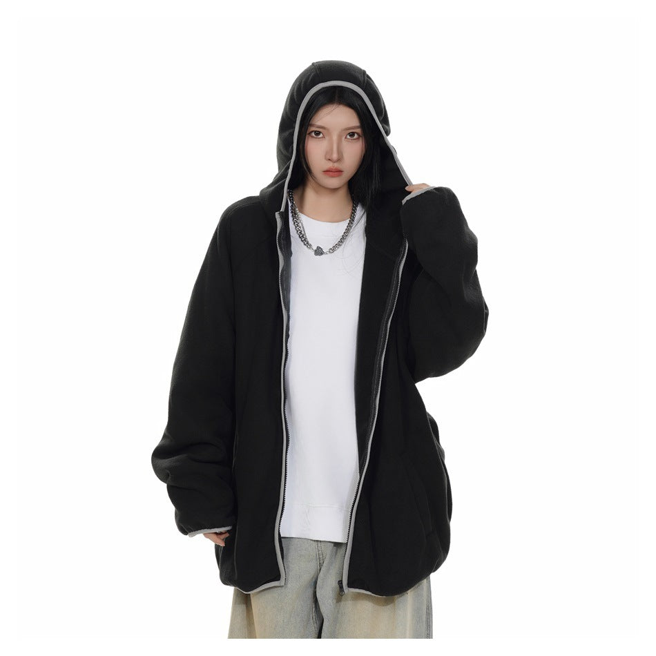 Model wearing an oversized black hooded zip jacket open over a white top, with gray trim and the hood up