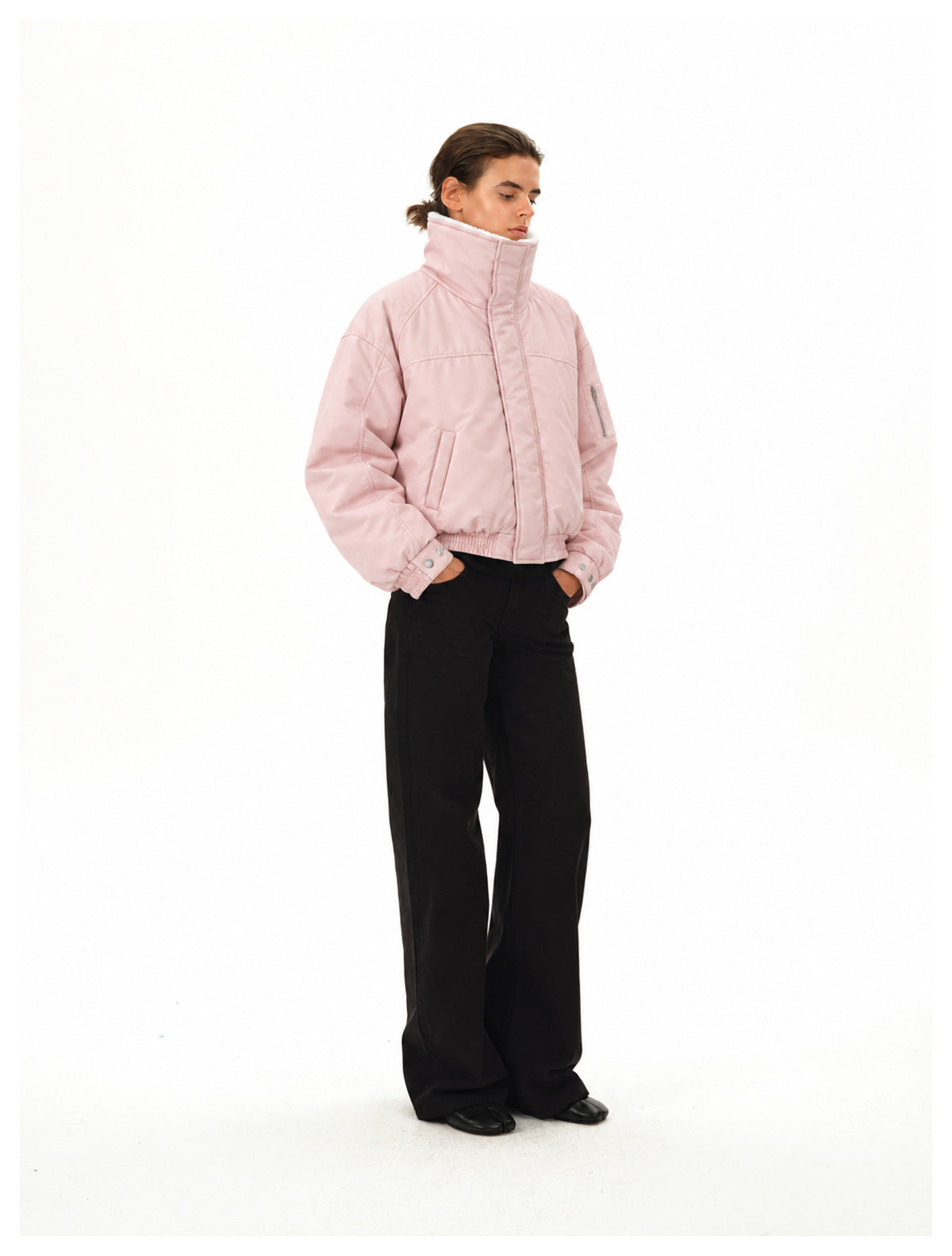 Model wearing the pink padded bomber jacket with upright collar, hands in pockets, with black wide-leg pants