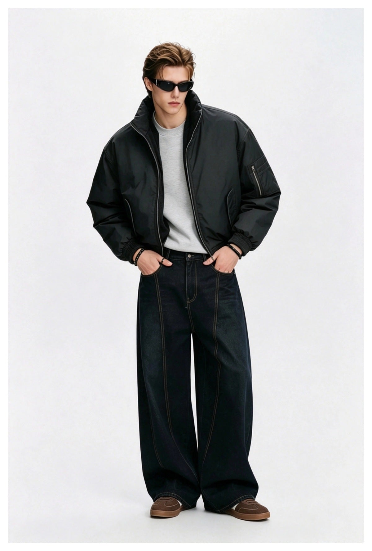 Model wearing the black bomber jacket open over a gray sweatshirt with wide-leg dark jeans and sunglasses