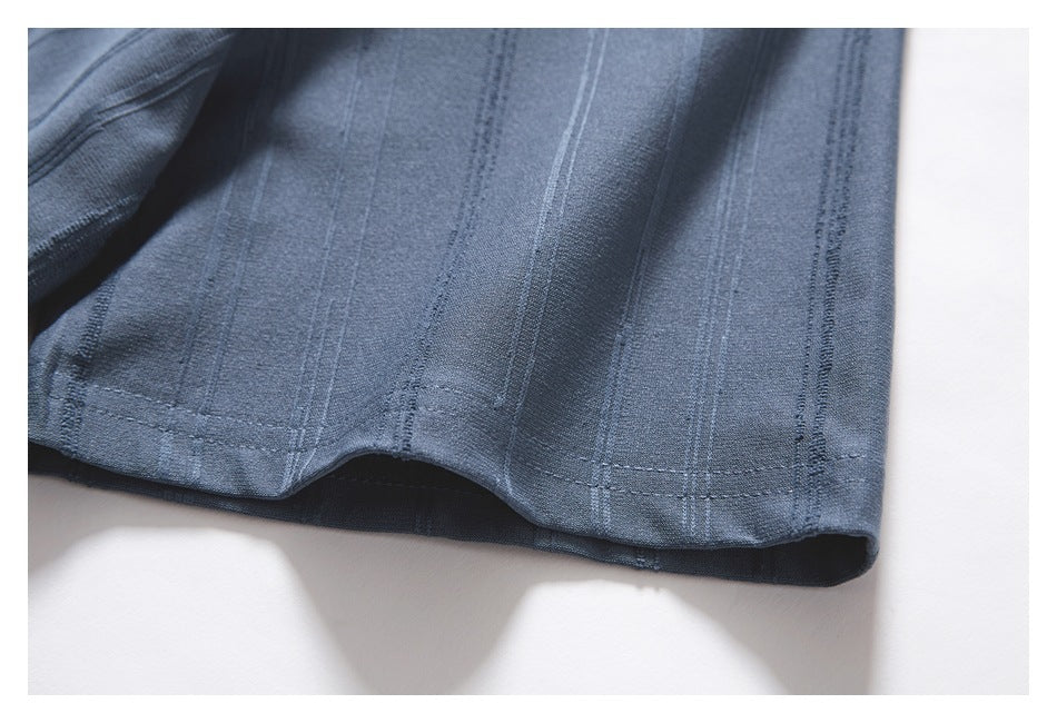 Close-up of the blue-gray top's hem and vertical textured stripe pattern.