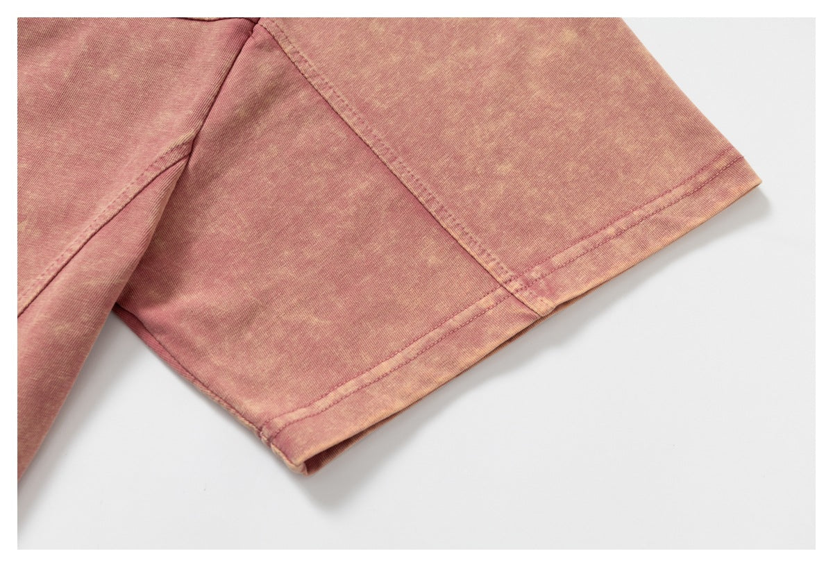 Close-up of the double-stitched sleeve hem on a mottled pink T-shirt.