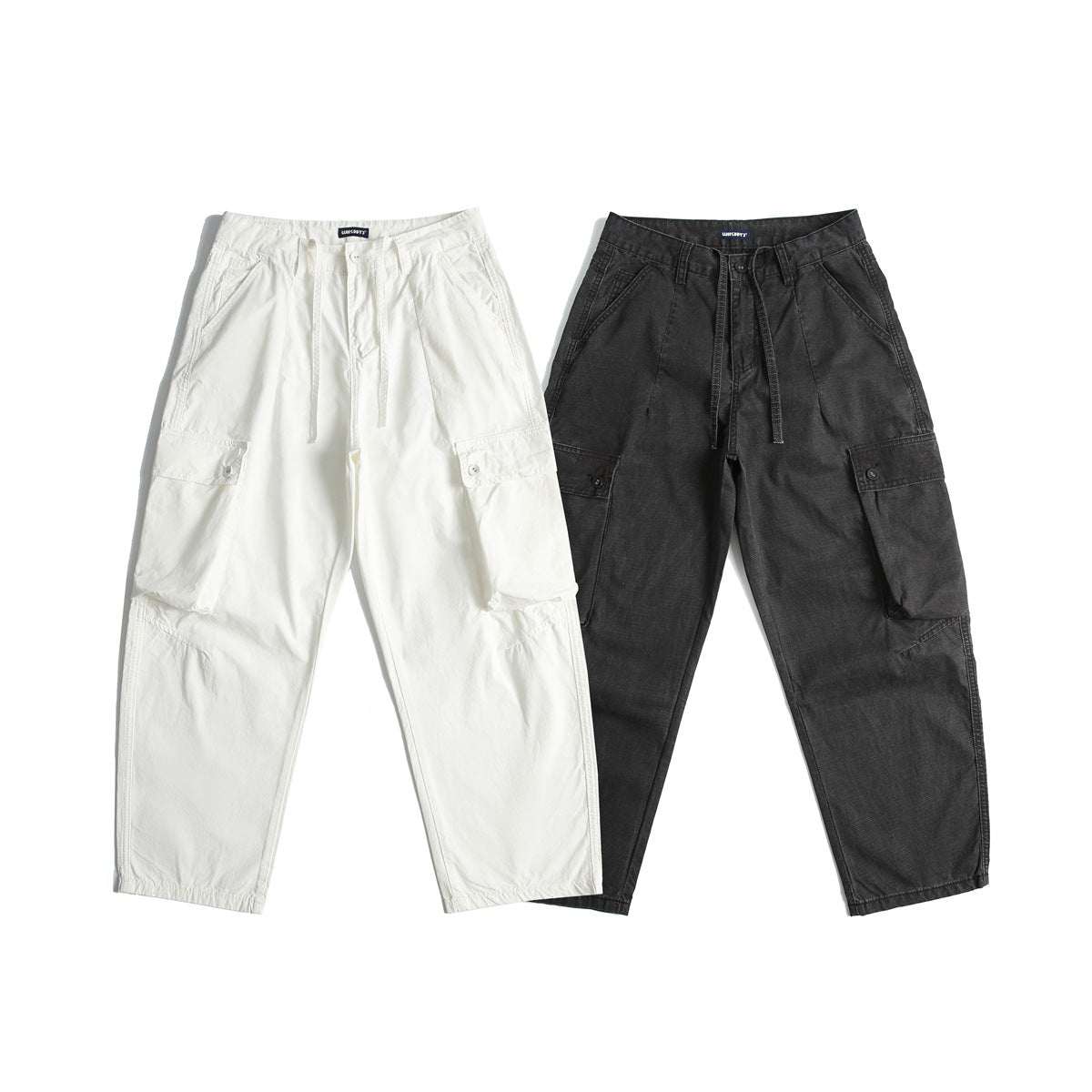 Front flat lay of relaxed cargo pants in off-white and charcoal, with drawstrings and large leg pockets.