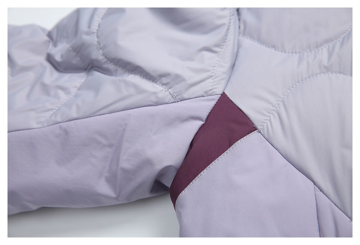Close-up of a lavender jacket's curved quilt seams and burgundy color-blocked side panel.