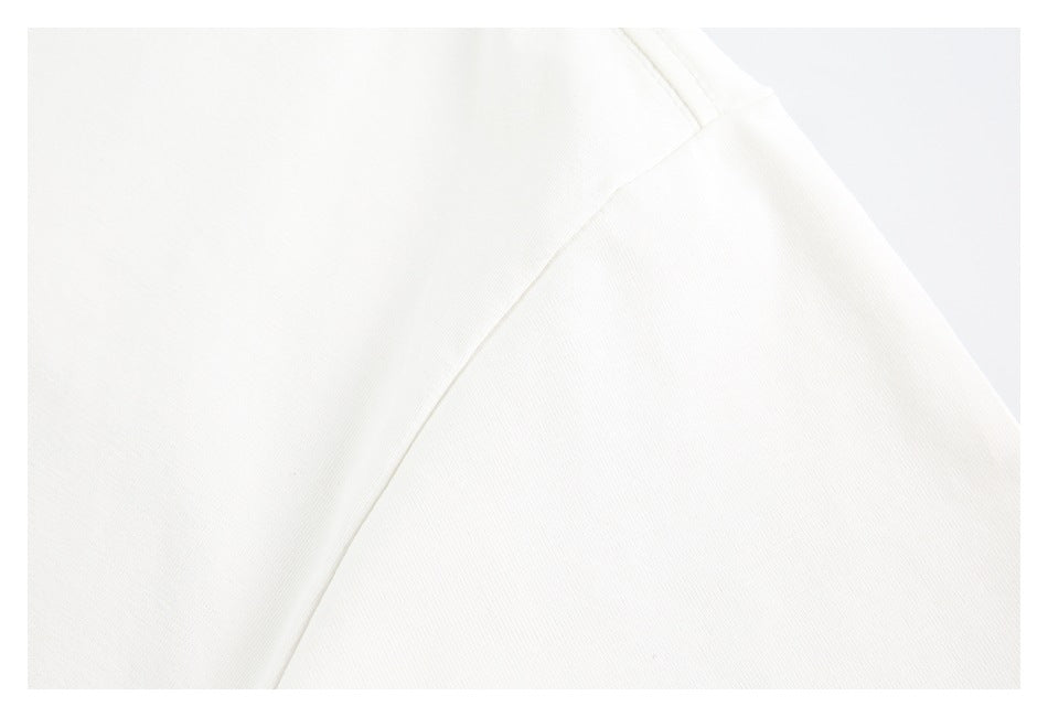 Close-up of off-white garment fabric showing a diagonal seam and shoulder stitching.
