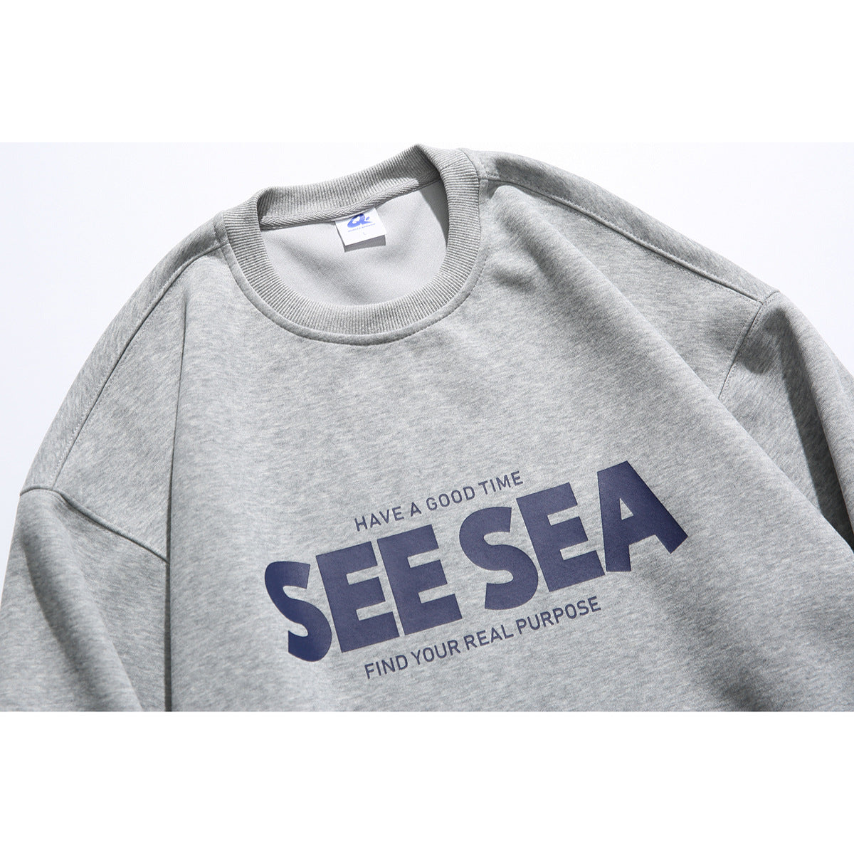Close view of a heather gray crewneck sweatshirt with navy “SEE SEA” text across the chest.