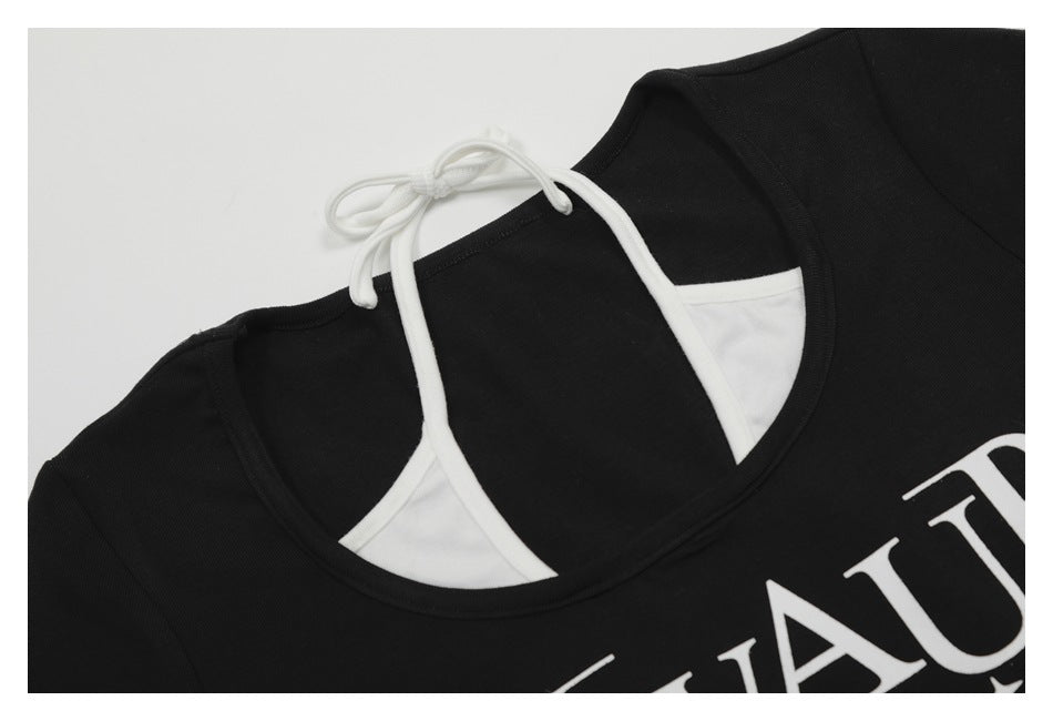 Close-up of a black top's neckline with white tie straps, white inset panels, and part of a white chest print.