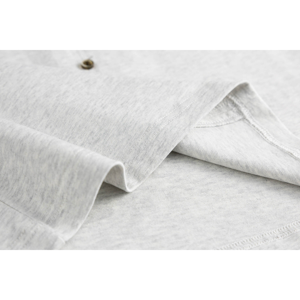 Close-up of light gray shirt fabric folded to show its stitching and inside seam.