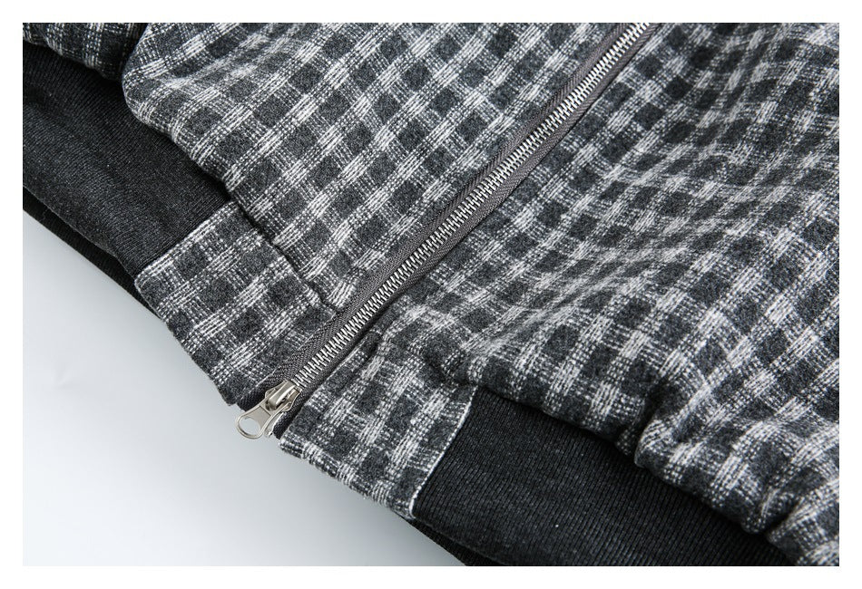 Close-up of a charcoal and gray plaid jacket with a metal zipper and black ribbed hem.