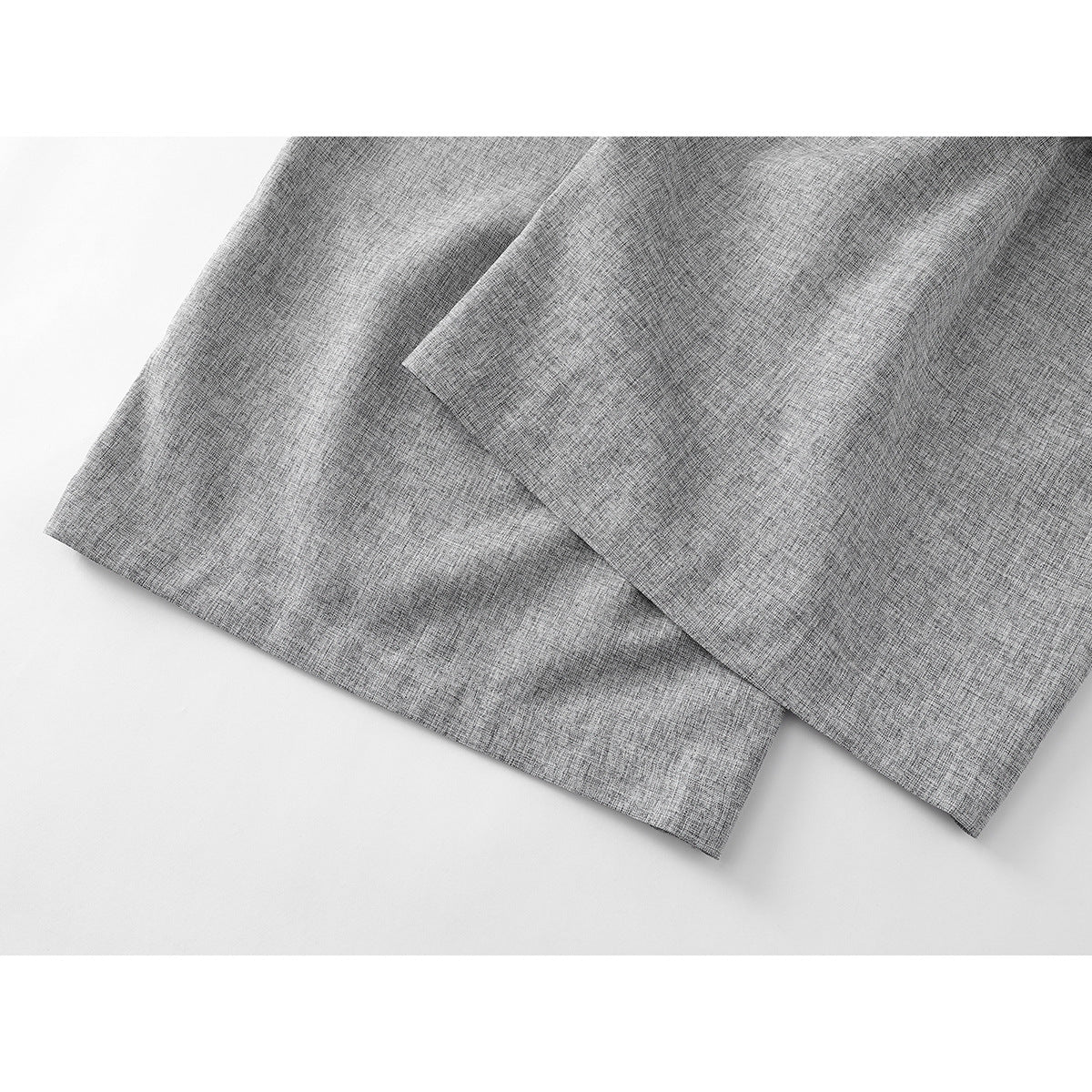 Close-up of the hem and overlapping wide-leg panels of gray trousers.