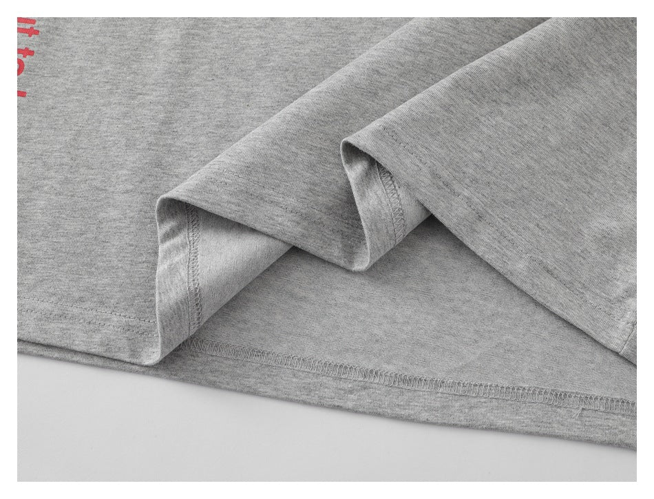 Close-up of the heather-gray T-shirt hem and sleeve, showing folded fabric and stitched seams.
