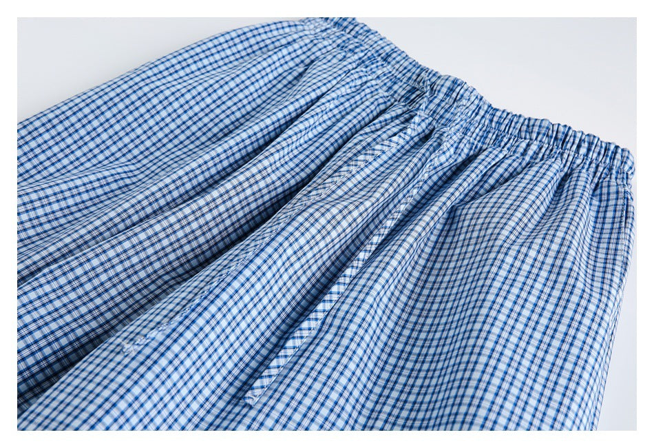 Close-up of blue-and-white checked pants showing the gathered elastic waistband and front seam.