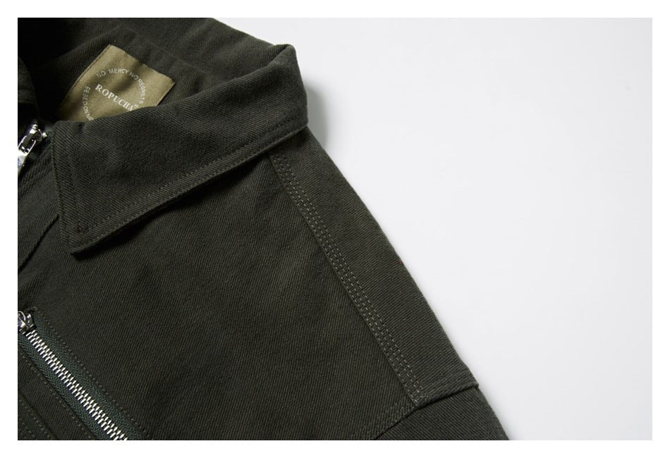 Close-up of the dark olive jacket's pointed collar, shoulder seam, and interior sewn label.