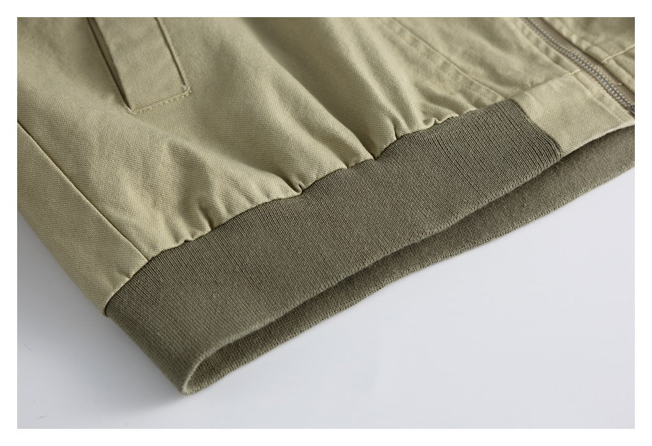 Close-up of a beige garment hem with gathered fabric and a wide dark olive ribbed band.