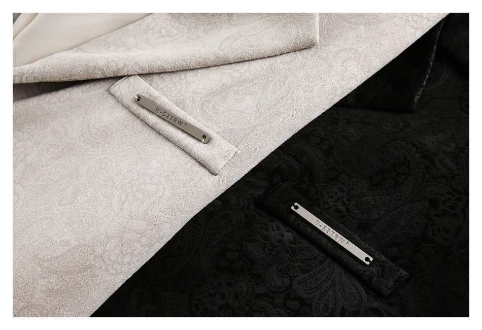 Close-up of light gray and black patterned blazer fabric with narrow metal plaques attached near the pocket areas.