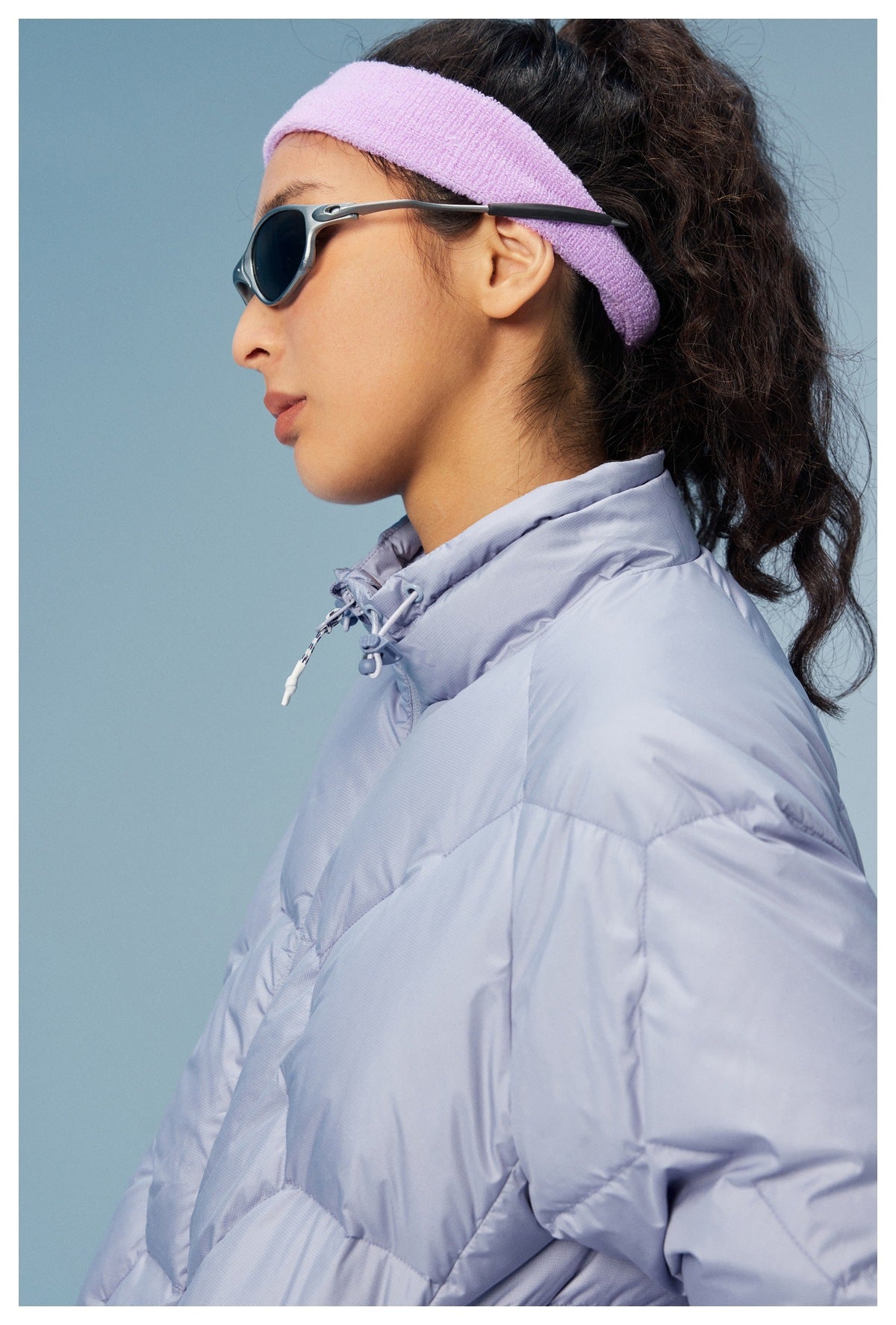Close-up of a pale lavender quilted jacket's high collar and drawcord adjustment, worn by a model.