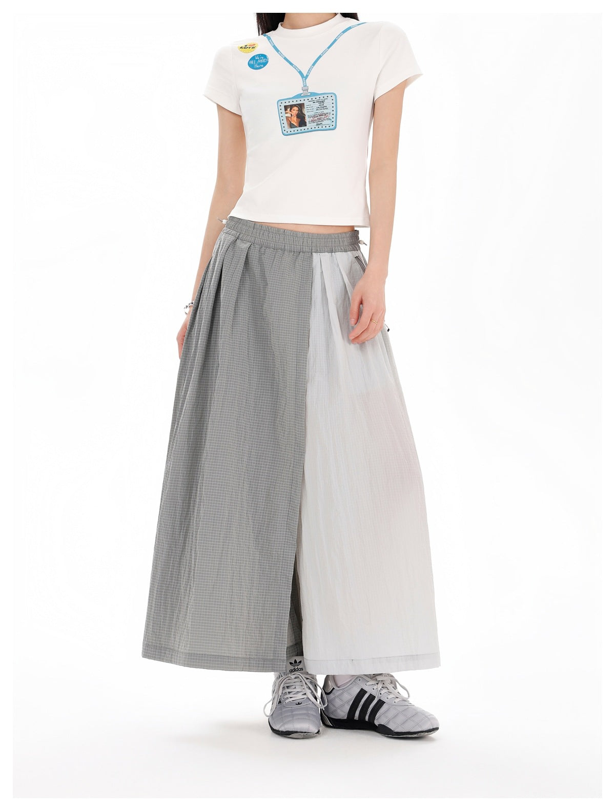 Model wearing the gray two-tone pleated wide skirt-pants with a white short-sleeve tee and gray sneakers