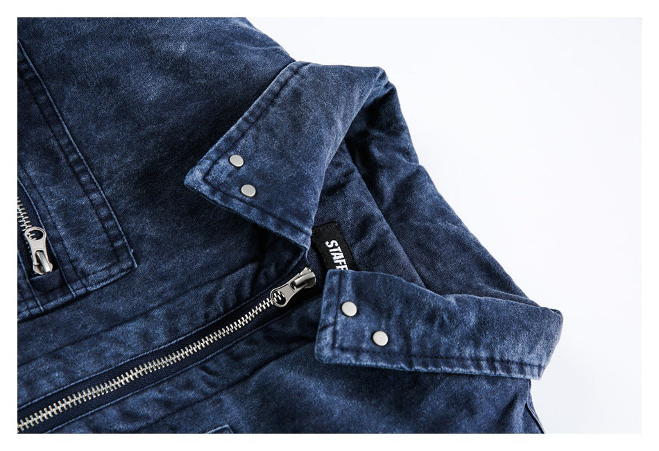 Close-up of the dark indigo jacket's silver zipper, snap-fastened cuff tabs, and seams.