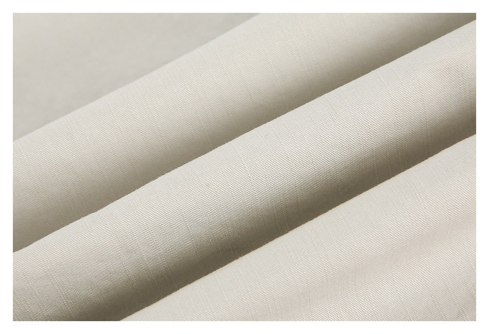 Close-up of softly folded off-white fabric showing its fine diagonal weave.