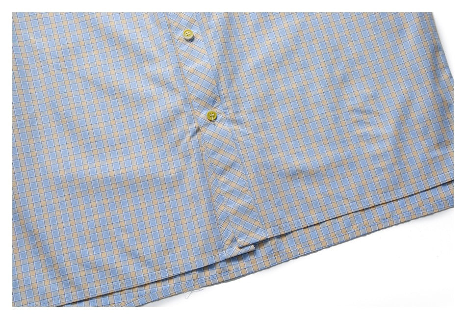 Close-up of the lower front of a light blue and beige plaid shirt, with button placket and hem.