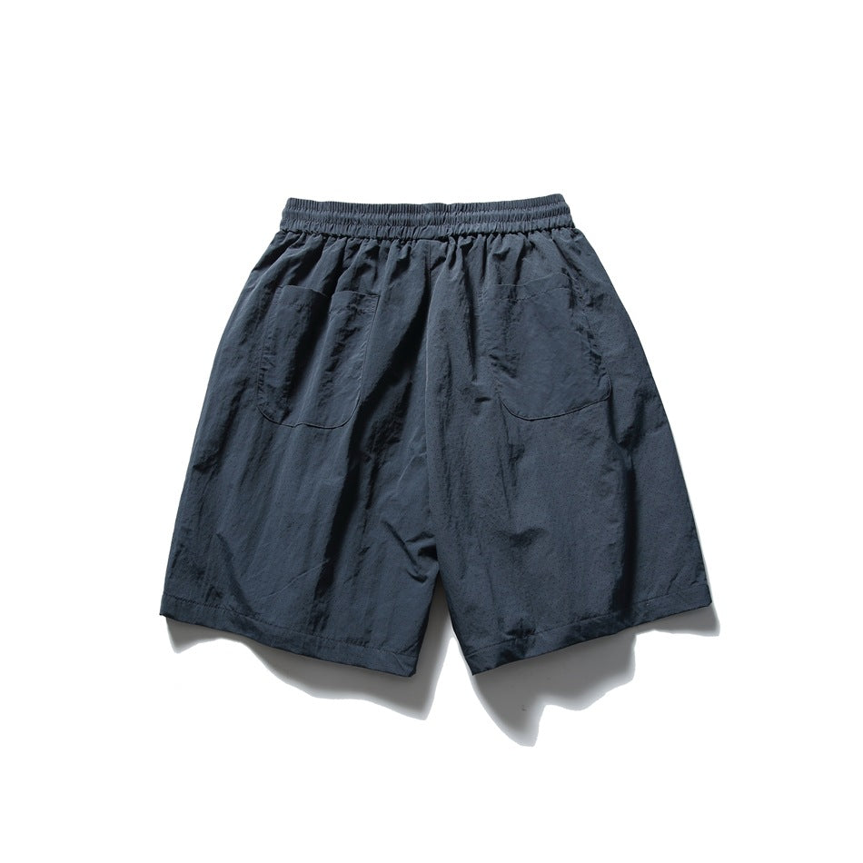 Dark navy shorts laid flat from the back, with an elastic waistband and two patch pockets.