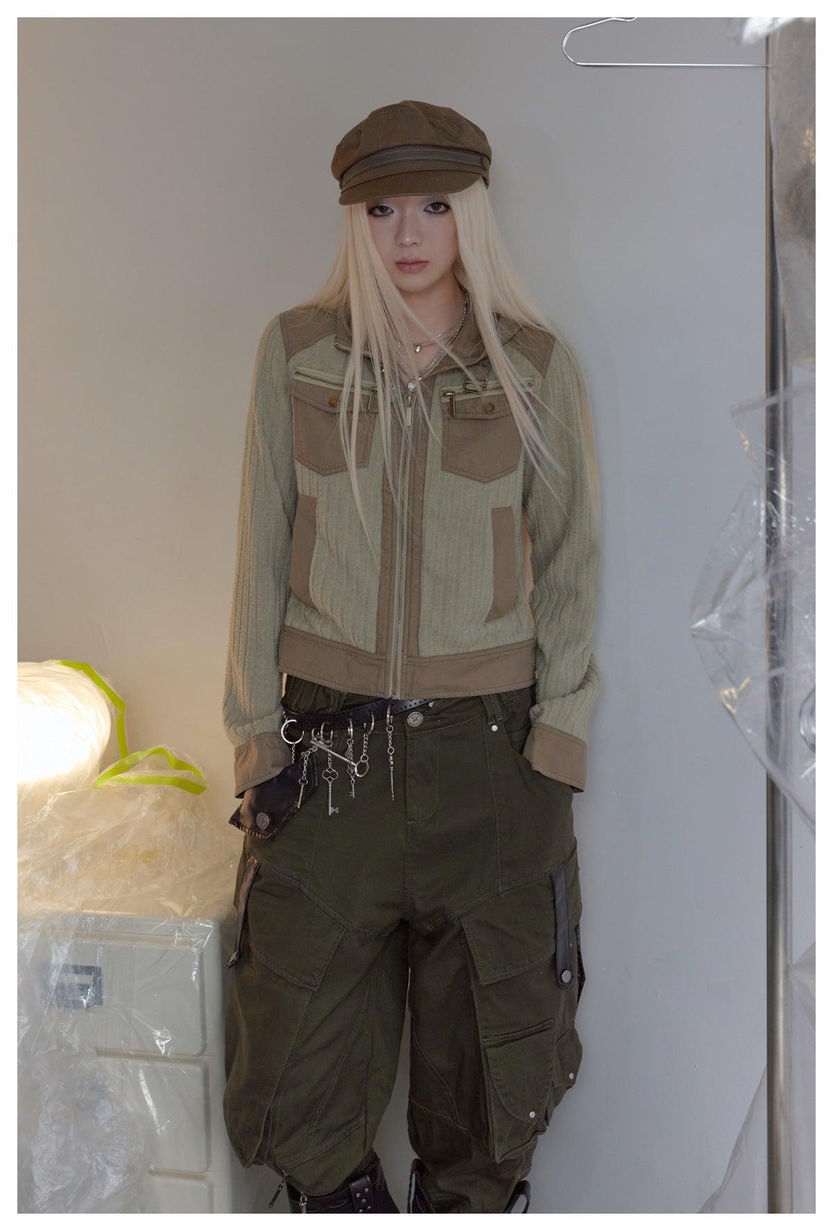 Front view of a model wearing a sage and tan hooded zip jacket with dark olive cargo pants.