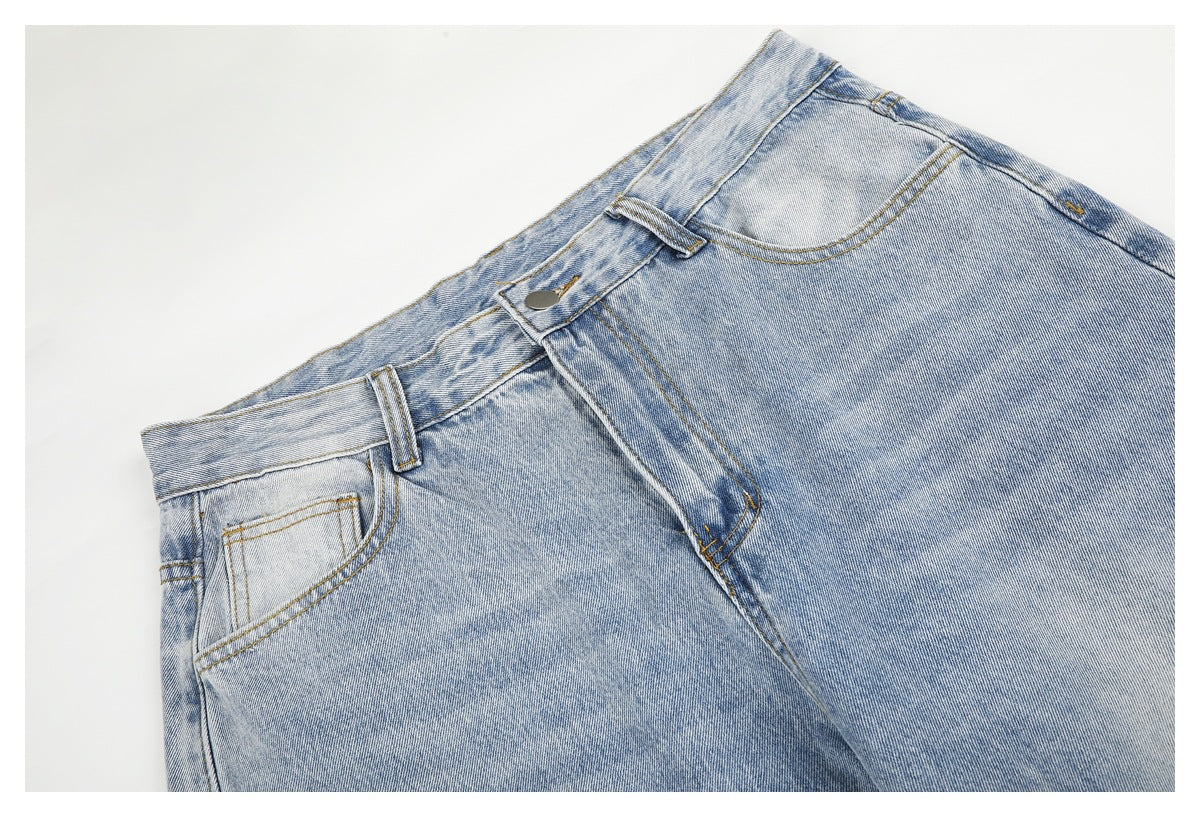 Close-up of the front waistband and pockets on light-wash jeans, with a button closure and contrast stitching.
