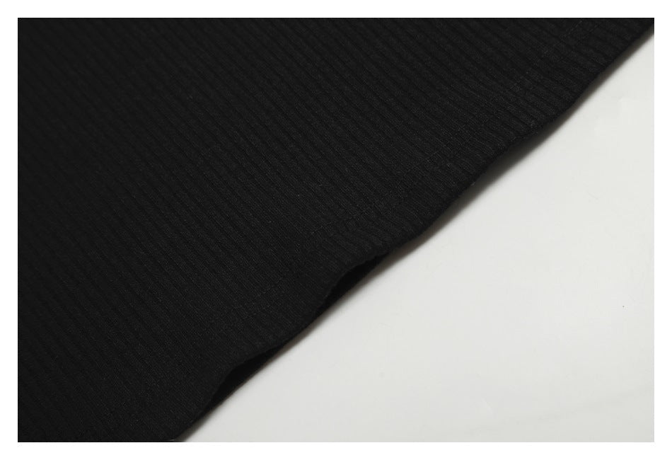 Close-up of black ribbed fabric and a curved stitched edge.