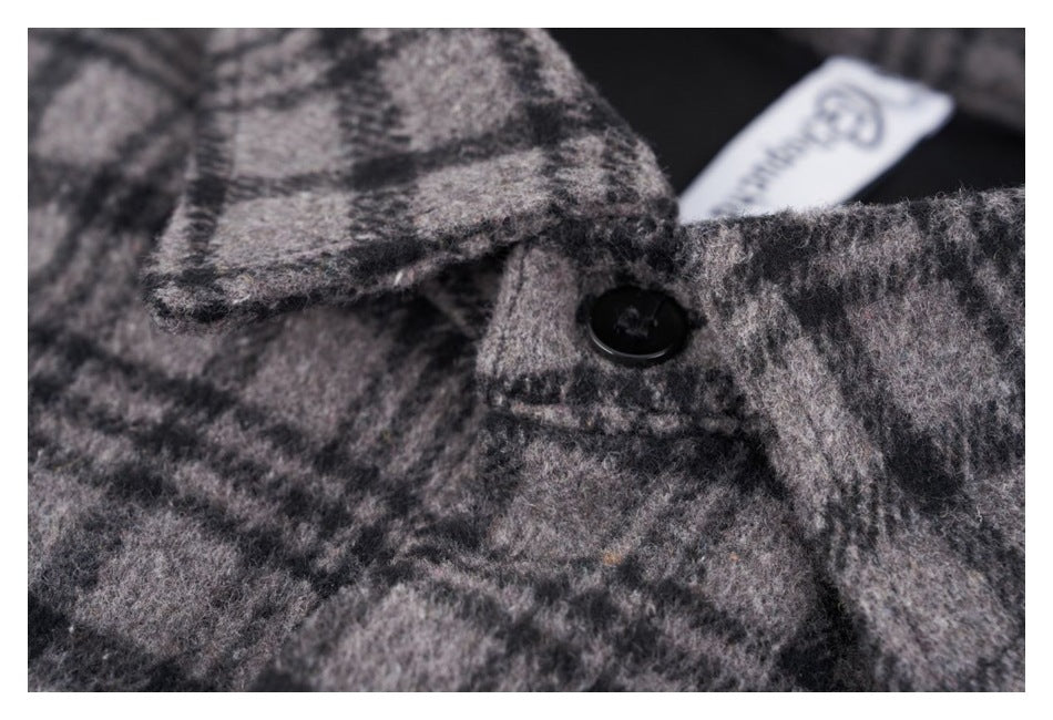 Macro view of a black button fastening the gray and black plaid shirt collar.