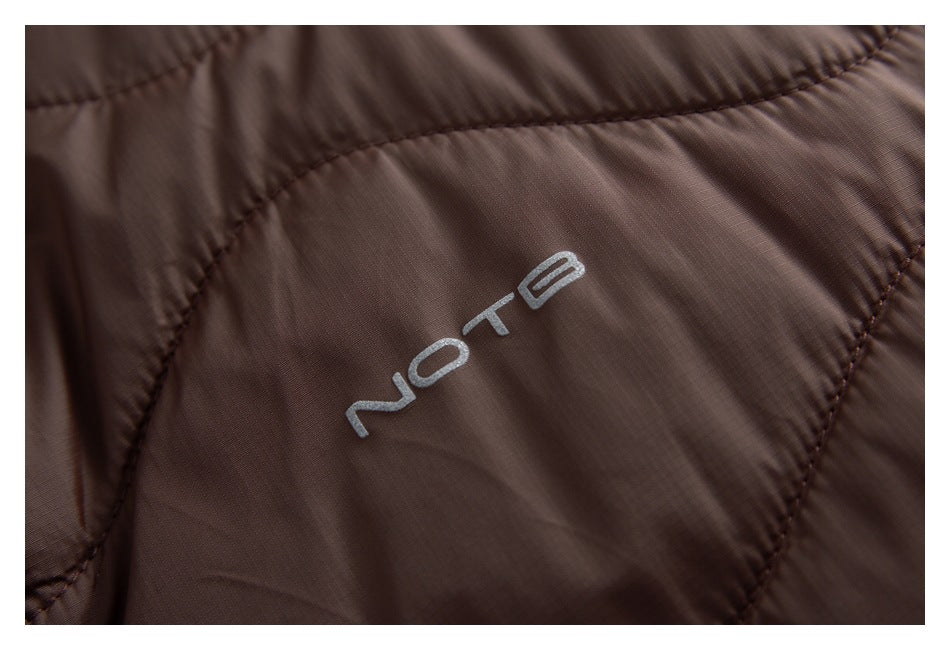 Close-up of a silver logo on brown quilted jacket fabric.