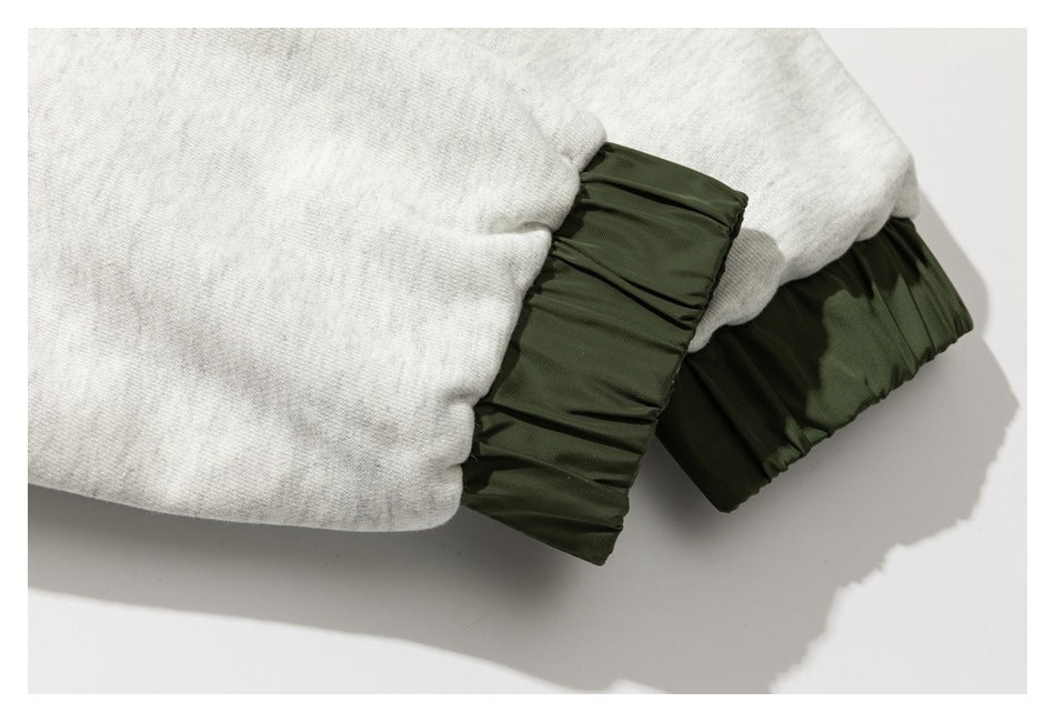 Close-up of a light gray sleeve ending in a dark olive gathered cuff.