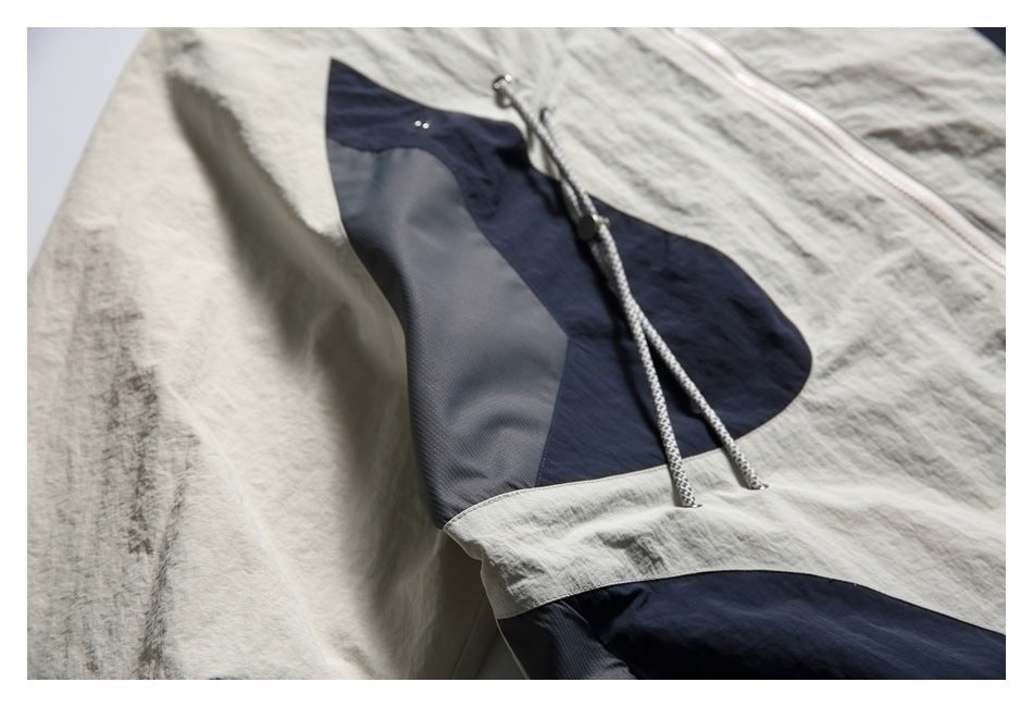 Close-up of a light beige and navy color-block jacket with patterned drawcords and a front pocket.