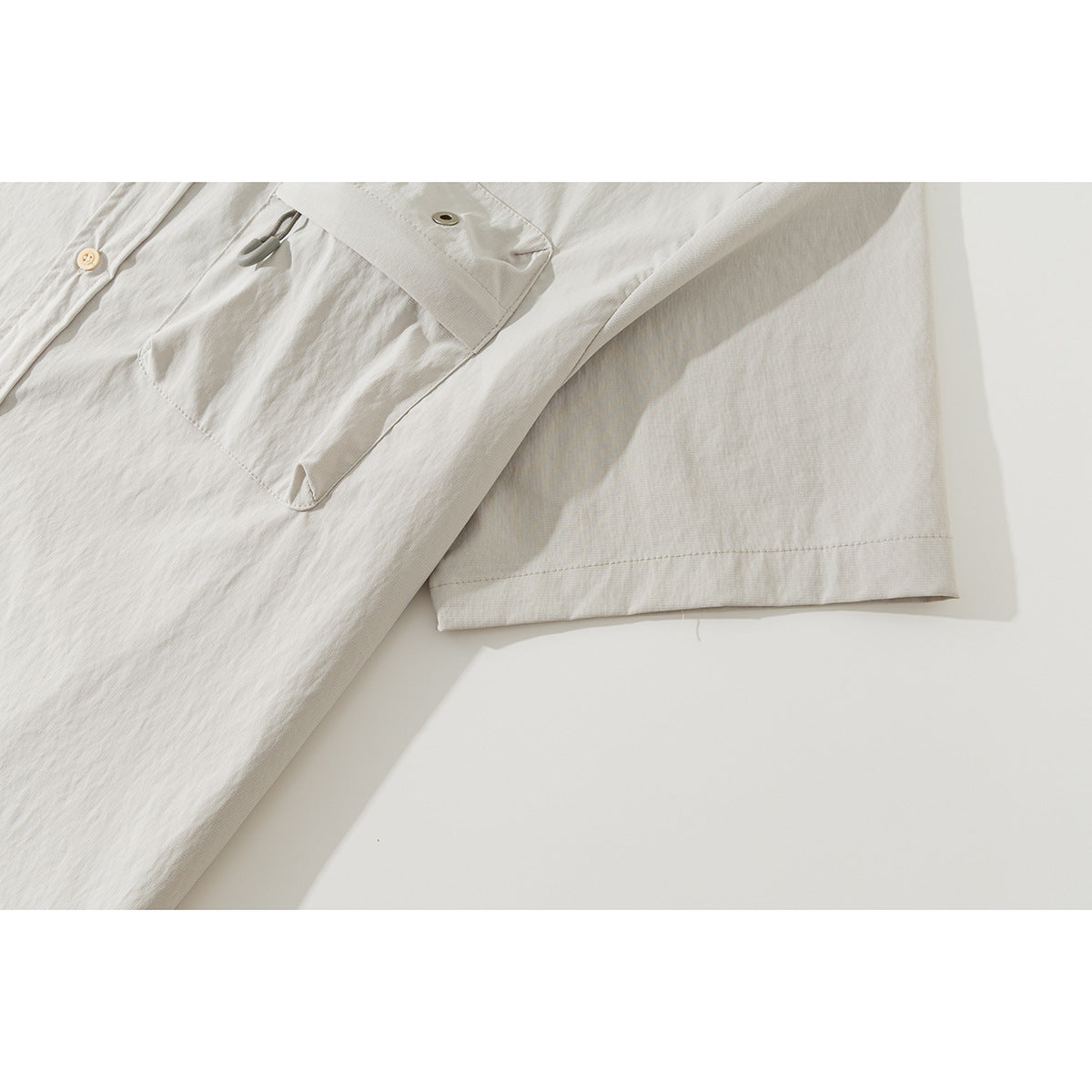 Close-up of an off-white shirt's short sleeve and chest pocket with a flap and small loop detail.