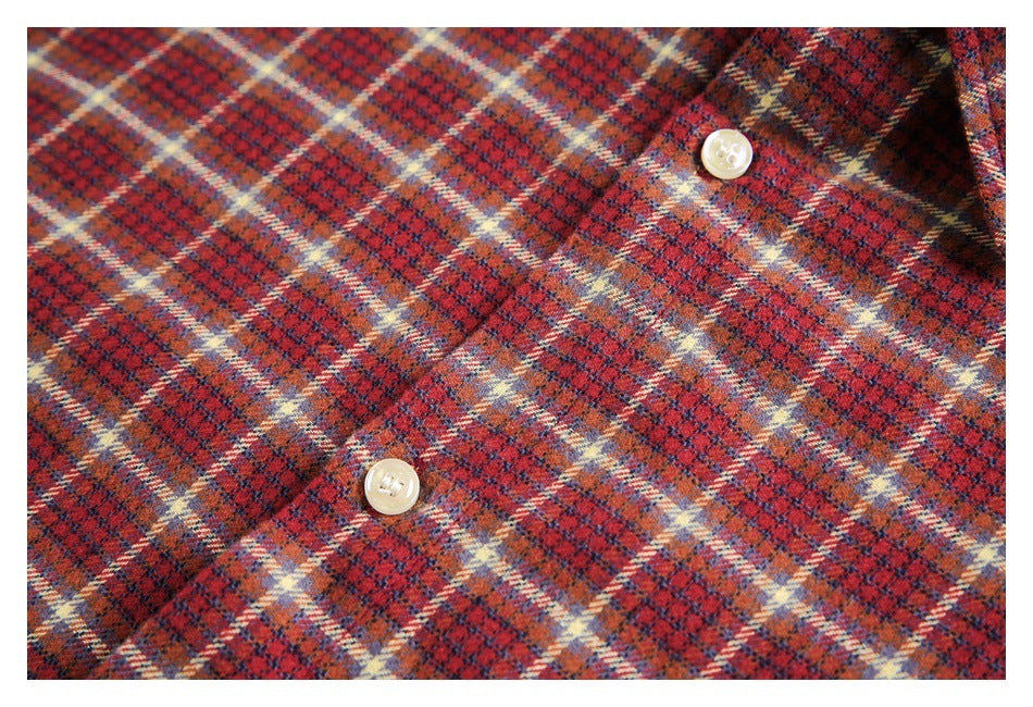 Close-up of a red, navy, and cream plaid shirt with two cream buttons.