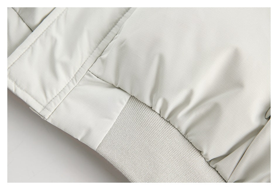 Close-up of a white jacket's ribbed knit hem and stitched panels.