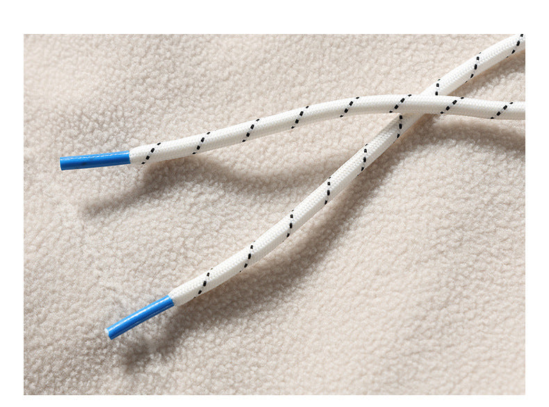 Close-up of white drawstrings with black dashed accents and blue tips against cream hoodie fabric.