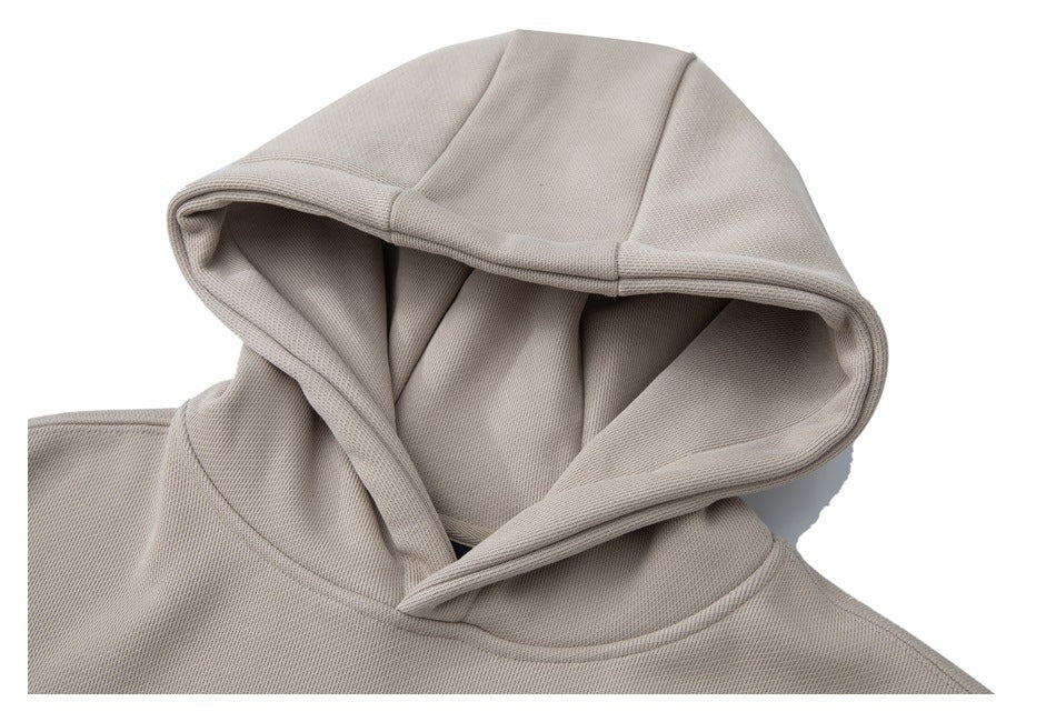 Close-up of the light taupe sweatshirt's hood, showing its panel seams and layered opening.