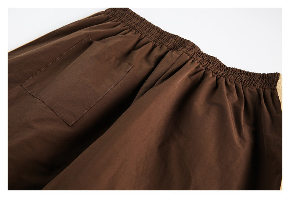 Close-up of dark brown pants showing the gathered elastic waistband and a large stitched pocket.