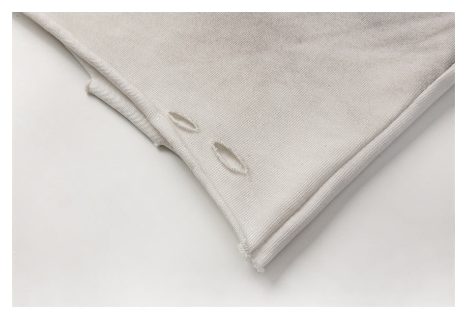 Close-up of a pale gray T-shirt hem with two small distressed slits and ribbed fabric.