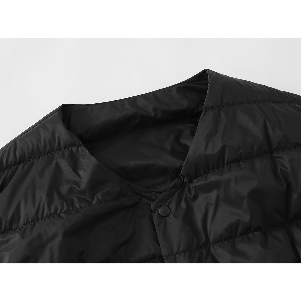 Close-up of a black quilted vest’s neckline and snap-button front.