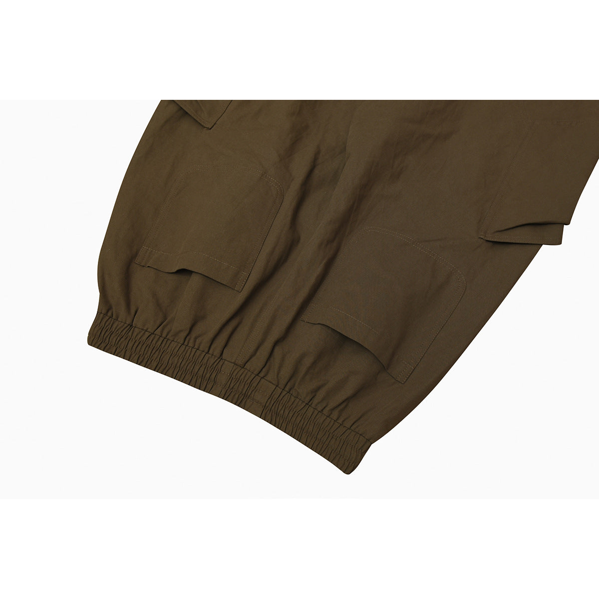 Close-up of olive-brown cargo pants with large stitched pockets and an elasticated leg opening.