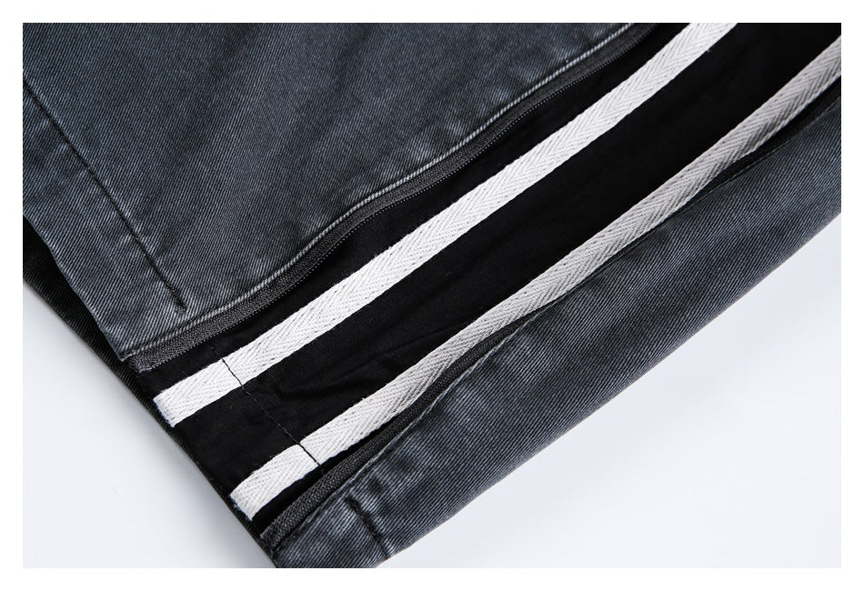Close-up of the opened leg zipper and contrasting light strips inside dark charcoal jeans.
