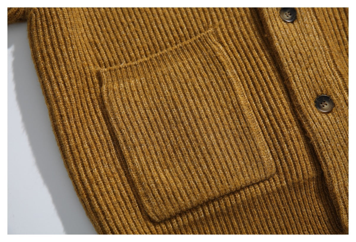 Close-up of a large patch pocket and dark buttons on a mustard-brown ribbed cardigan.