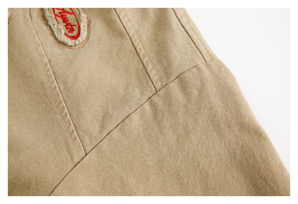 Close-up of a tan jacket sleeve with stitched panel seams and part of an embroidered patch.