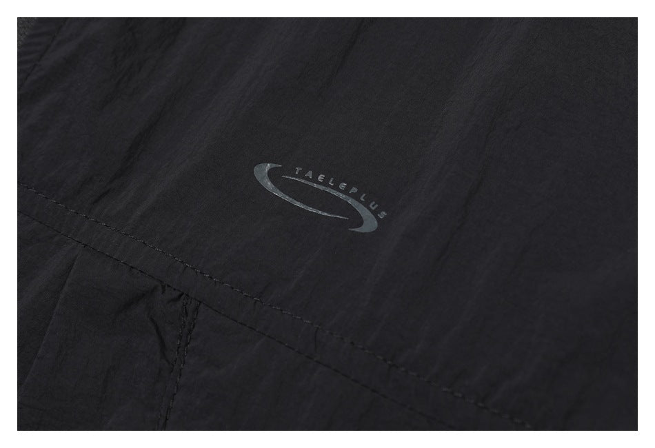 Close-up of a small gray swoosh-style logo printed on black fabric.