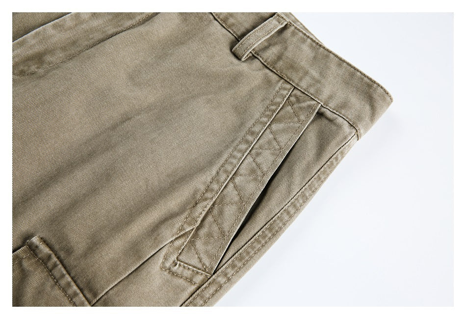 Close-up of a taupe trouser side pocket with decorative crisscross stitching and a belt loop.