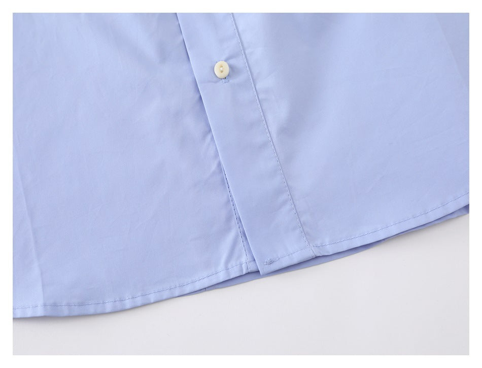 Close-up of the light blue shirt's lower front placket, button, and curved hem.