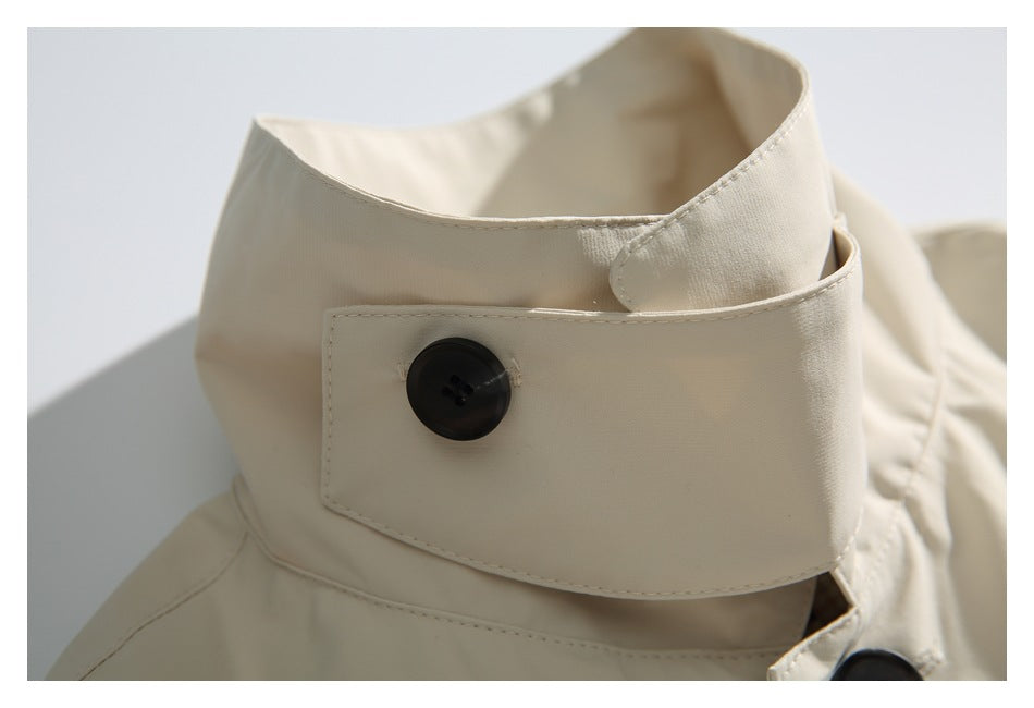 Close-up of an ivory coat collar with a wide buttoned tab and dark button.