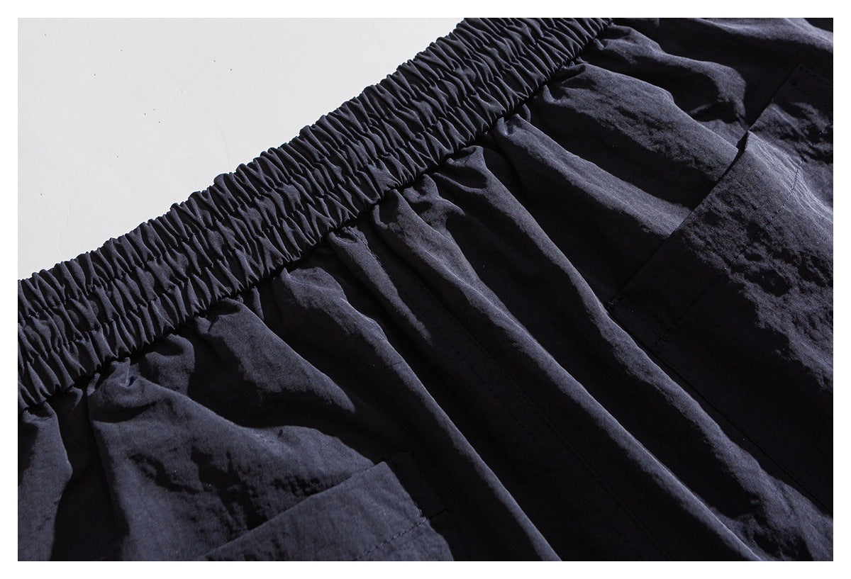 Close-up of the gathered elastic waistband and pleated fabric on dark shorts.